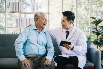 Handsome doctor consults senior patient at clinic office. Medical work use tablet read record on a...