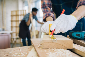 Close up, Handsome carpenter define and measure dimensions timber of house wooden interior accessories for further refinement within building or condominium. Construction learning concept. Soft focus