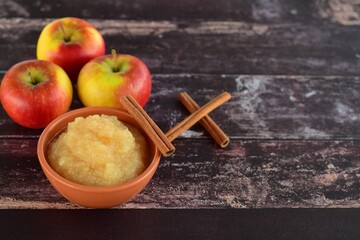 bowl of apple sauce with fresh apples and cinnamon sticks