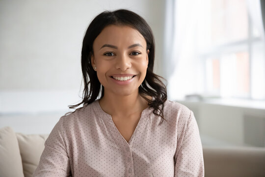 Profile picture of smiling African American young woman renter or tenant look at camera at home. Headshot portrait of happy biracial female employee talk on video call, have webcam meeting online.