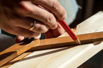 the man draws a line with a pencil on the construction Board measuring the desired angle