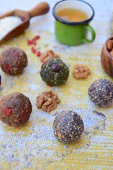 Homemade healthy raw vegan assorted energy balls with seeds, almond nuts, walnuts, goji berry, spirulina, coconut, cacao powder, acai berry and dates. Served with tea