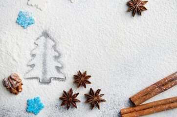 Christmas kitchen background made of flour, cinnamon sticks, anise,  cookie cutter and sugar sprinkles