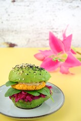 Healthy vegan avocado burger with red cabbage, spinach, chickpea cauliflower patties and tahini sprinkled with sesame seeds. Selective focus