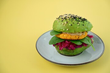 Healthy vegan avocado burger with red cabbage, spinach, chickpea cauliflower patties and tahini sprinkled with sesame seeds. 