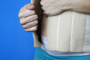 Postpartum rehabilitation. A woman puts on a corset.