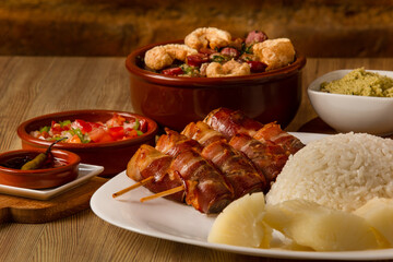 typical Brazilian barbecue, dish with chicken with bacon, rice, farofa, feijão tropeiro, beens, cassava
