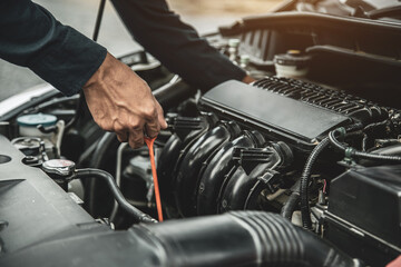 Auto mechanic are checking vehicle engine oil level to changing car engine oil concepts of maintenance repair service and car insurance.