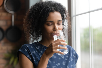 Happy young African American woman feel dehydrated thirsty drink clean pure mineral water from...