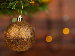 Brown Christmas ball with sparkles on the Christmas tree. Blurred background of garlands.
