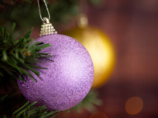 Purple Christmas ball on the Christmas tree. Blurred background of golden Christmas ball.