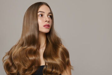 beautiful woman with large wavy hair and makeup. On a gray background