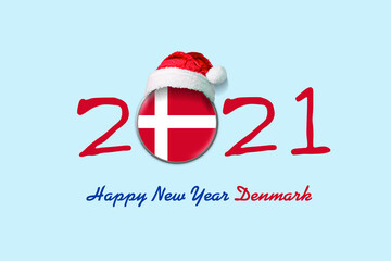 2021. Happy New Year Denmark. Flag of Denmark in a round badge, and in a Santa hat. Isolated on a light blue background. Design element.