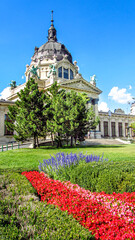 Entrance of the medicinal baths in City Park, Budapest in summer. Botanical garden with colorful flowers in front of hungarian building. Touristic destination.