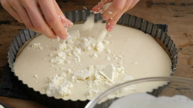Greek cheese pie. Woman prepares a pie with feta cheese. Black background.