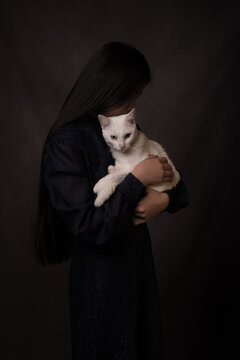 Classic lovely studio portrait of girl holding white cat  in painterly dark Rembrandt style