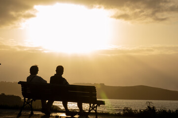 Fototapeta na wymiar Silhouette of a couple sitting by the sea watching the sunset 
