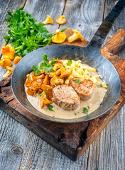 Modern Style traditionelle gebratene Medaillon Filets vom Schwein in Rahmsauce mit Pfifferlingen und Spätzle angeboten als close-up in einer rustikalen schmiedeeisernen Pfanne