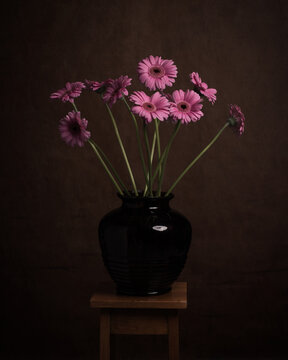 Classic autumn studio still life with pink gerbera flowers in vase in dark painterly rembrandt style