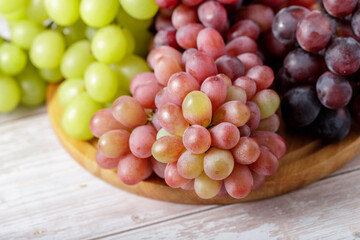 Various color bunch fresh grapes on wooden board.