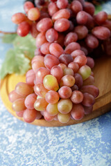 Large bunch fresh pink red lady fingers grapes on wooden board