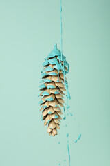 Blue paint dripping out of pine cone. Creative Fall minimal concept. Autumn background.