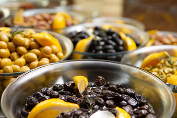 Glass bottle of homemade olive oil and olive tree branch, raw turkish green and black olive seeds and leaves on grey rustic table. olives background, olivae oleum