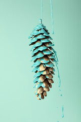 Blue paint dripping out of pine cone. Creative Fall minimal concept. Autumn background.