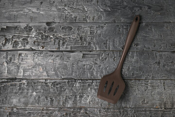Brown silicone chef's spatula on a wooden background.