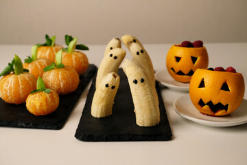 Healthy fruit Halloween treats. Banana ghosts, tangerines fake pumpkins, orange pumpkinhead Jacks