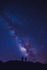 Fototapeta na wymiar Silhouette of couple on the hill. Stargazing at Oahu island, Hawaii. Starry night sky, Milky Way galaxy astrophotography.