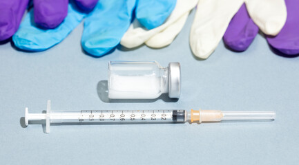 Vaccination and immunization concept syringe with ampoules, colored gloves