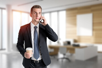 Businessman with coffee on phone in office