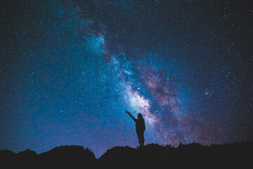 Naklejka na ściany i meble Silhouette of girl / woman standing on the hill. Stargazing at Oahu island, Hawaii. Starry night sky, Milky Way galaxy astrophotography.