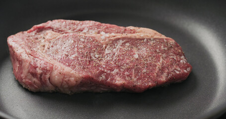 Closeup shot of ribeye steak frying on non stick pan