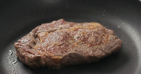 Closeup shot of ribeye steak frying on non stick pan