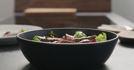 ribeye steak slices in salad in black bowl