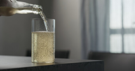 man pour soda drink from a bottle into highball glass on concrete countertop with copy space
