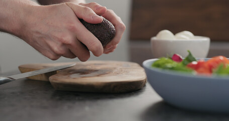 man open avocado for a salad on olive wood board