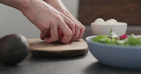 Closeup man takes tomato halves from olive wood