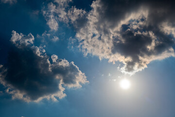 Sun and black clouds in the dark blue sky