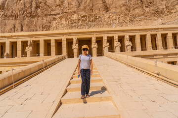 Fototapeta na wymiar A young woman on the entrance stairs to the Funerary Temple of Hatshepsut in Luxor. Egypt