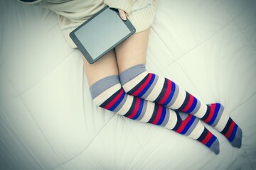 woman in long socks lying down using tablet or e-book