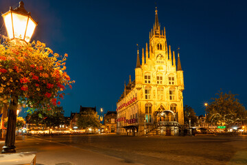 Famous city hall in gothic style on the market square in the old town of Gouda, Holland is illuminated at night. Selective focus.