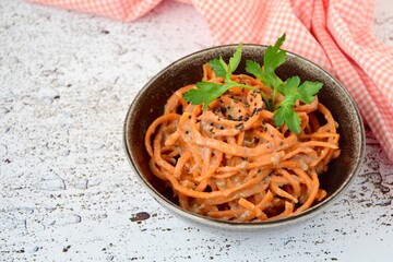 Fresh raw organic spiralized carrot noodle with tahini, parsley and sesame seeds