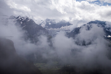 Mountains in the Valais Alps of Switzerland covered with fog on a summer day. 