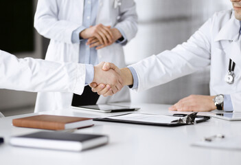 Unknown doctors are shaking their hands as agreement about patient's diagnosis, close-up. Medical help, insurance in health care, medicine concept