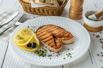 Grilled Fish with lemon and herbs on wooden white aged background