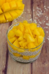 Mango coconut chia seeds pudding in glasses on wooden background