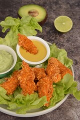 Gluten free chicken strips breaded with coconut flakes and spice served with mustard honey dip and avocado lime dip